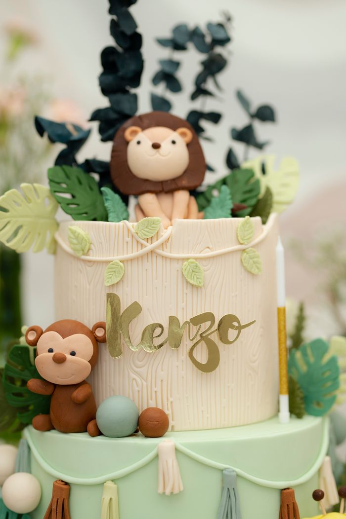 Adorable jungle-themed layer cake with lions and monkeys as decor, perfect for celebrations.